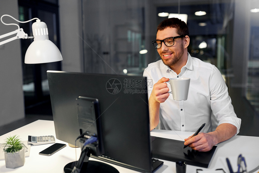 商业,平技术微笑的商人师与电脑笔碑黑暗的夜晚办公室喝咖啡师用钢笔平板电脑办公室喝咖啡图片