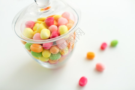 食物,糖果糖果的璃瓶与彩色糖果滴白色背景用五颜六色的糖果滴璃瓶图片