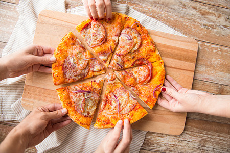 食物,人饮食近距离的手分享切片自制比萨饼木桌上把手收来,木桌上分享比萨饼图片