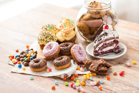 垃圾食品,糖果健康的饮食釉甜甜圈,巧克力,滴糖果块蛋糕木桌上桌子上同的糖果图片