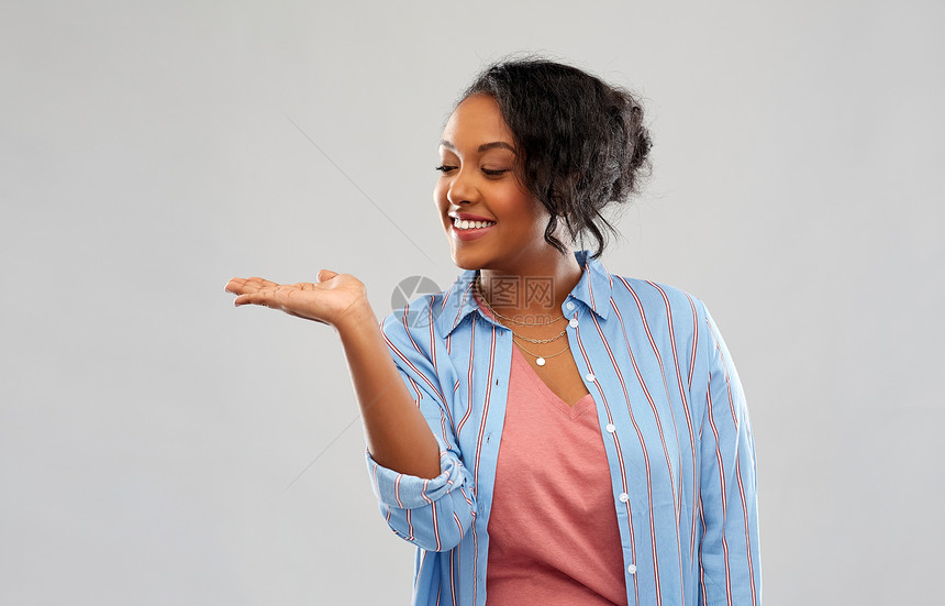 人广告快乐的非裔美国轻女人着些想象的东西空着手粉红色的背景快乐的非洲女人手里着东西图片