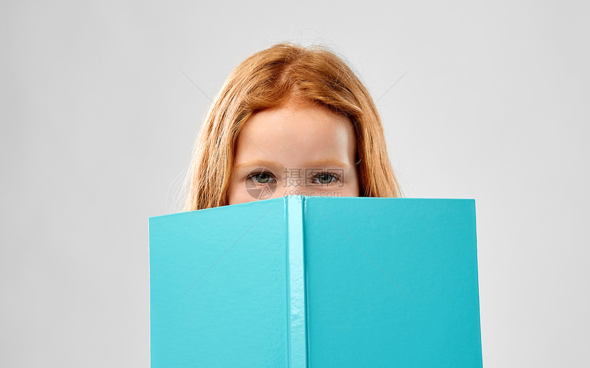 童人的微笑的红头发女孩阅读书灰色的背景微笑的红头发女孩看书图片