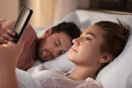技术,网络成瘾欺骗女人晚上用智能手机,而她的男朋友正睡觉女人男朋友睡觉时用智能手机设计图片