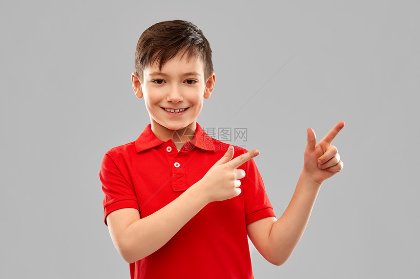 童,想法人的快乐的小男孩穿着红色马球T恤,手指灰色的背景下穿着红色T恤的快乐男孩指着边图片