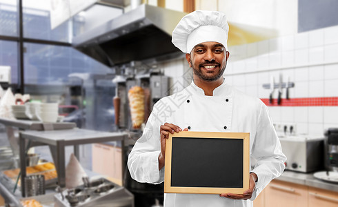 烹饪,职业人的快乐的印度男厨师托克与空白黑板菜单上的烤肉店厨房背景快乐的印度厨师烤肉店用黑板背景图片