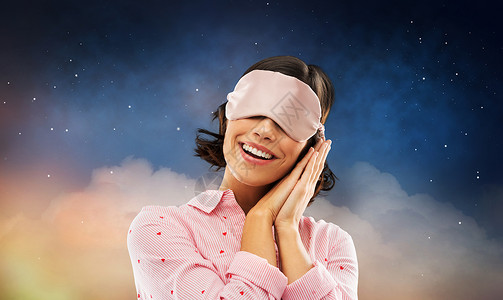 人们睡觉时间的快乐的轻女人睡衣眼罩星空背景快乐的轻女人穿着睡衣眼罩图片