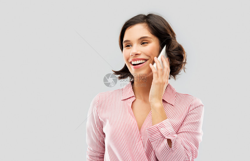 时尚,风格人的快乐的微笑轻妇女穿条纹衬衫,打电话智能手机灰色背景穿着条纹衬衫的轻女人智能手机上打电话图片