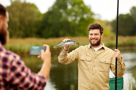 钓鱼休闲的人用智能手机拍摄渔夫朋友图片