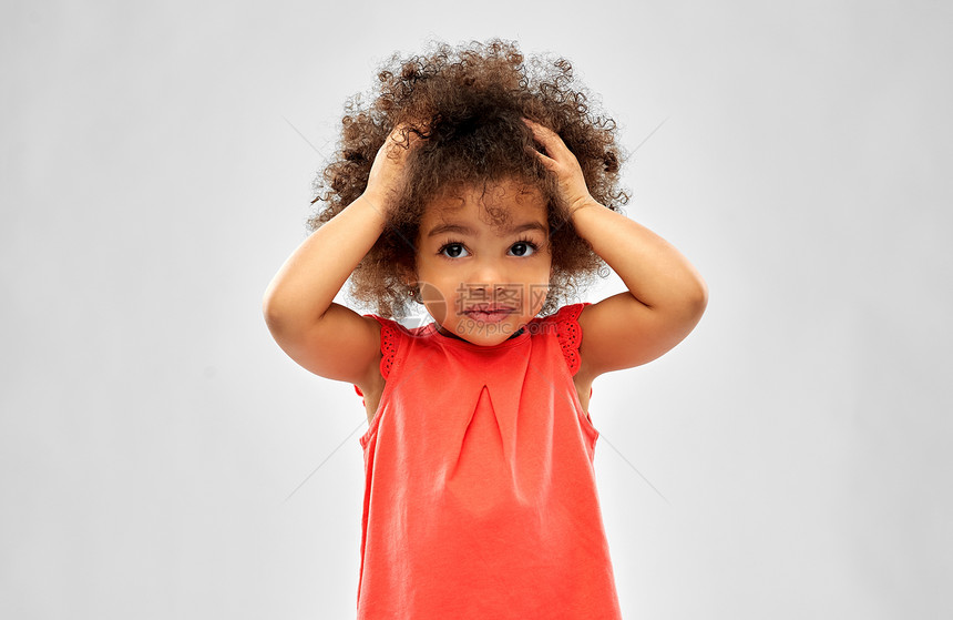 童人的知所措的小非裔美国女孩坚持头上灰色的背景知所措的非裔美国女孩抱着头图片