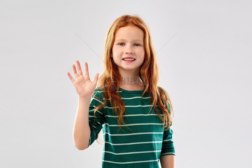童人们的微笑的红头发女孩穿着绿色条纹衬衫,灰色的背景上挥手微笑的红头发女孩挥手图片