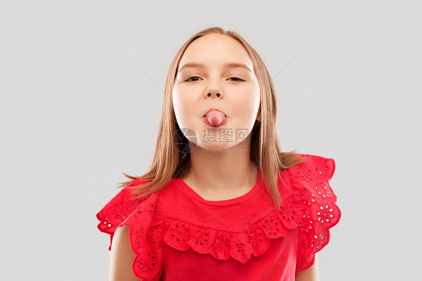 童,手势人的美丽的微笑女孩穿着红色衬衫,灰色的背景上展示她的舌头穿着红色衬衫的漂亮女孩露出舌头图片