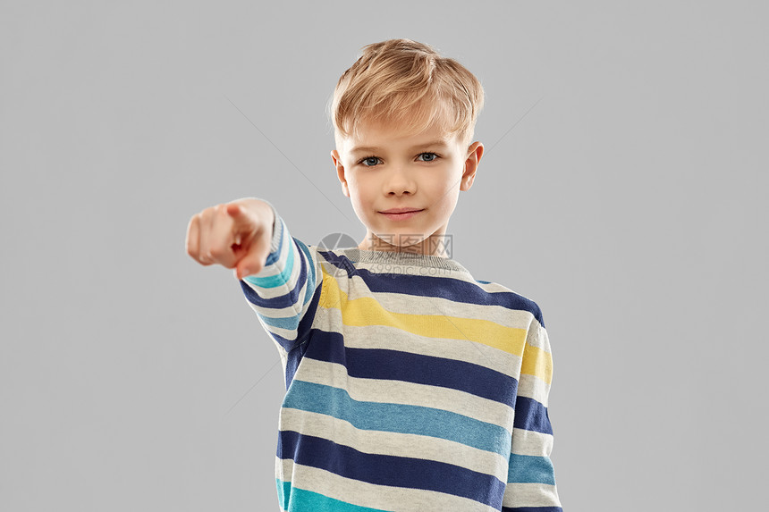 童,手势人的微笑的小男孩穿着条纹套头衫,手指指向灰色背景带条纹套衫的微笑男孩指着手指图片