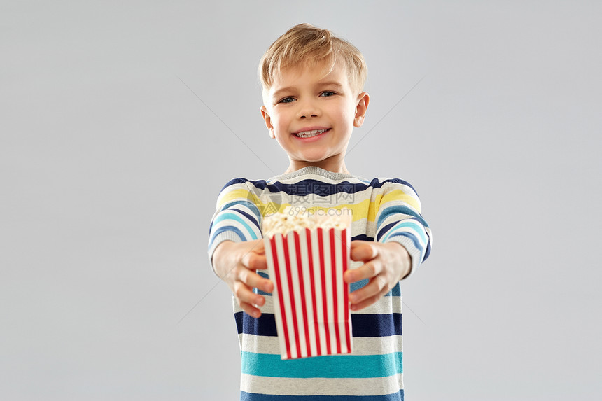 快餐,健康的饮食童的小男孩穿着条纹套头衫,着爆米花纸桶灰色背景小男孩着纸桶爆米花图片