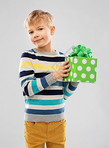 生日,童人的微笑的小男孩与礼品盒灰色背景带生日礼物盒的微笑男孩图片