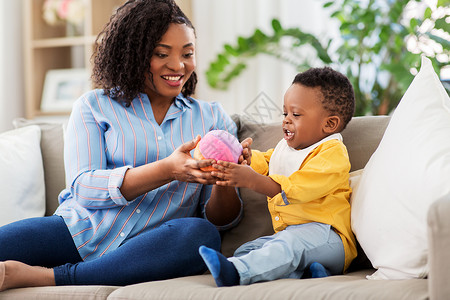 童,孩子人的快乐的非裔美国母亲她的小儿子家里沙发上玩球妈妈宝宝家玩球图片