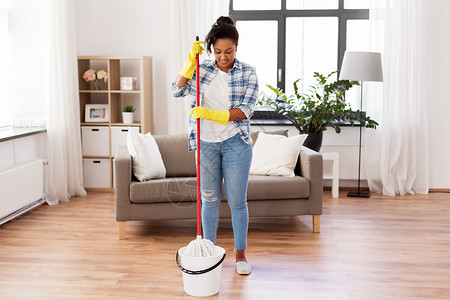 家务家务非裔美国妇女家庭主妇把拖把浸泡桶里,家打扫地板非洲妇女家庭主妇家清洁地板背景图片