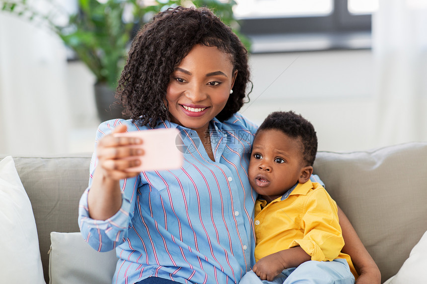 家庭,技术母亲的快乐的微笑轻的非裔美国母亲与小儿子家里用智能手机自拍非洲母亲带着小儿子家自拍图片