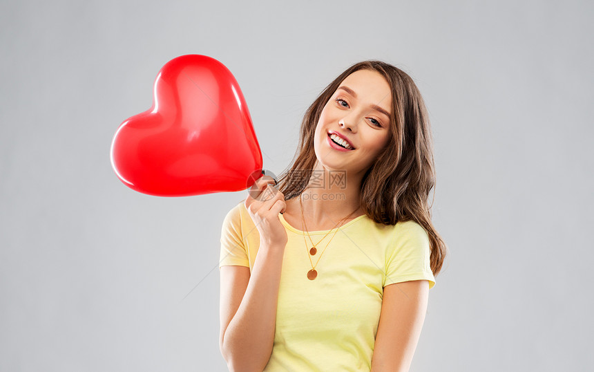 情人节人们的微笑的轻女人十几岁的女孩穿着黄色T恤,红色心形气球灰色背景上带红色心形气球的十几岁女孩图片
