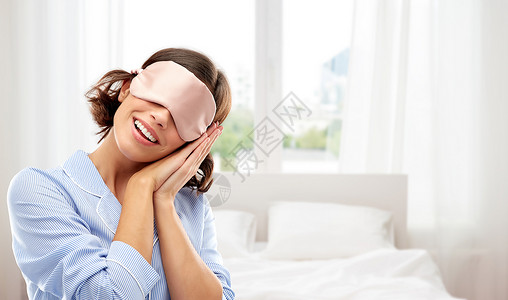 人们睡前快乐的轻女人睡衣眼罩的背景快乐的轻女人穿着睡衣眼罩图片