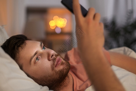 轻人躺床上用智能手机图片