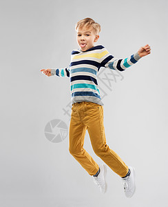 童人们的漂亮的小男孩条纹套头衫跳跃玩灰色背景快乐的小男孩跳跃,玩得开心图片