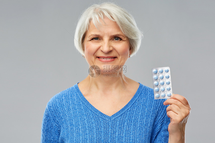 微笑的老年女性展示手上的药片图片