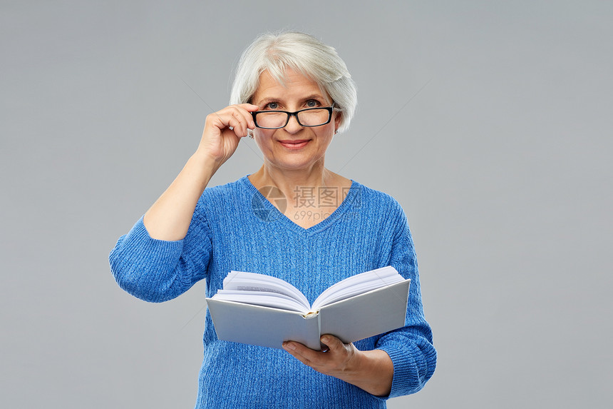 老妇女戴眼镜阅读书图片
