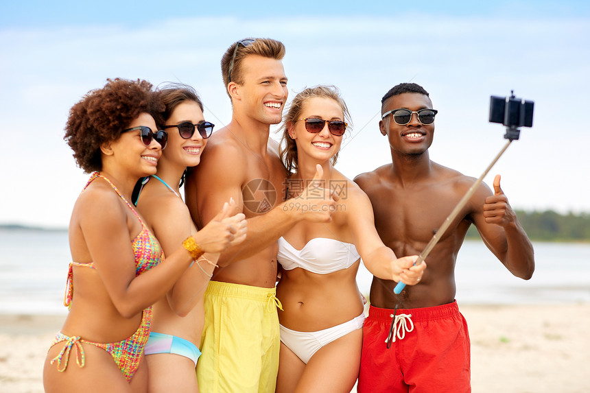 友谊,暑假人们的群快乐的朋友用智能手机海滩上的自拍杆上拍照,竖大拇指朋友们海滩上自拍,竖大拇指图片