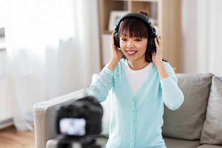 博客,视频博客人的亚洲女博客与相机记录视频审查耳机家带耳机的女博主制作视频博客背景图片