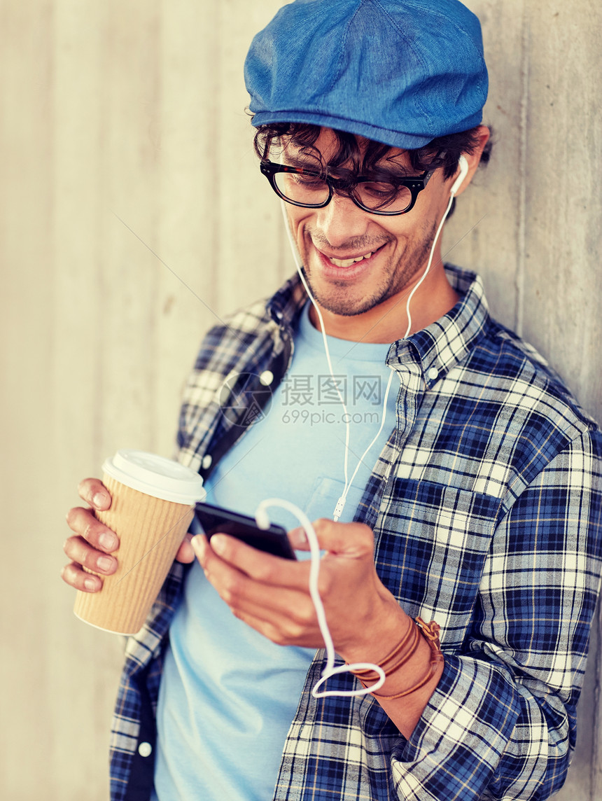 人技术休闲生活方式城市街道上用耳机智能手机喝咖啡听音乐的快乐微笑的人带着耳机智能手机的男人喝咖啡图片