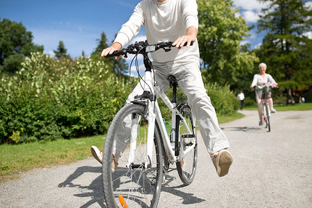 积极的老,人生活方式的快乐的老人骑固定自行车夏季公园快乐的老人夏季公园骑自行车背景图片