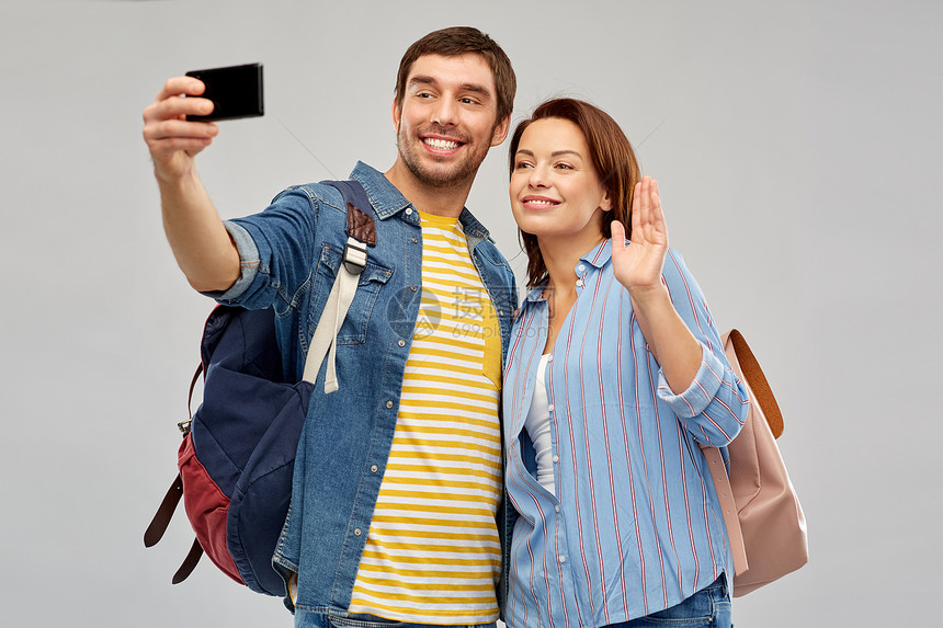 旅行,旅游度假快乐的游客与背包采取自拍智能手机灰色背景几个游客用智能手机自拍图片