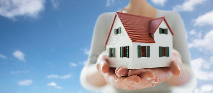 房地产,住宿财产近距离的手房子家庭模式蓝天云的背景双手紧握房屋家庭模型图片