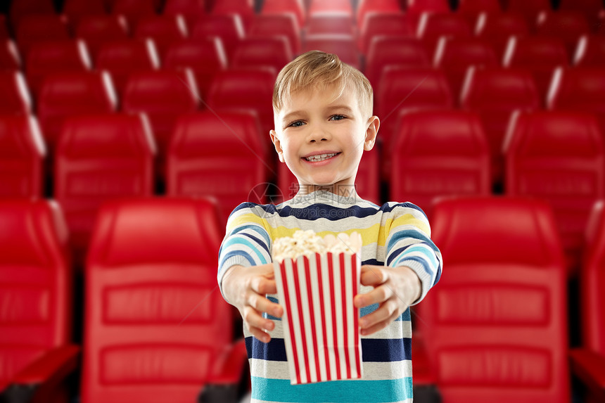 电影,快餐娱乐活动小男孩穿着条纹套头衫,着纸桶爆米花电影院的背景电影院着纸桶爆米花的男孩图片