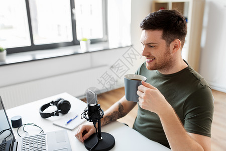技术,大众媒体播客快乐的男音频博客与笔记本电脑麦克风,喝咖啡广播家庭办公室拥笔记本电脑麦克风音频博客的博背景图片