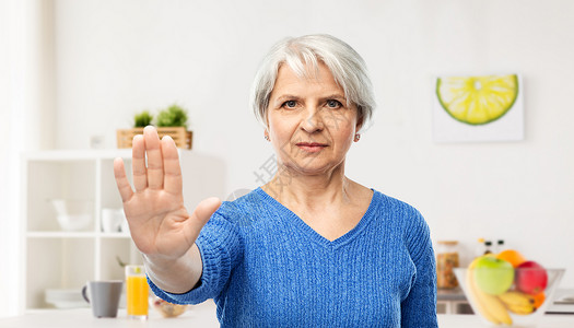 在厨房的老年女人表示禁止的手势图片