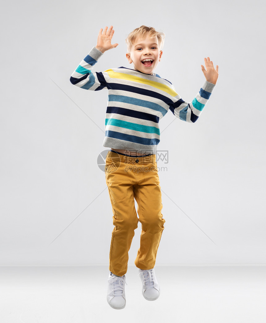 童人们的漂亮的小男孩条纹套头衫跳跃玩灰色背景快乐的小男孩跳跃,玩得开心图片