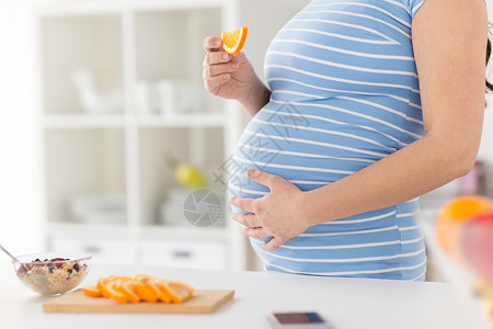 怀孕,健康食品人们的密切孕妇家里厨房吃橙色早餐孕妇家吃橘子图片