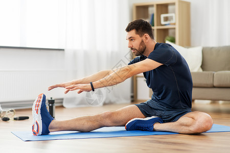 运动,健身健康的生活方式男人伸展腿运动垫家里男人家里用运动垫伸展腿图片