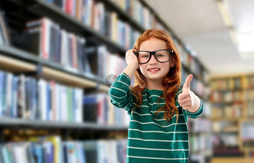 教育,视觉阅读微笑的红色头发学生女孩戴着眼镜绿色条纹衬衫图书馆背景图书馆戴眼镜的红头发微笑的女孩图片