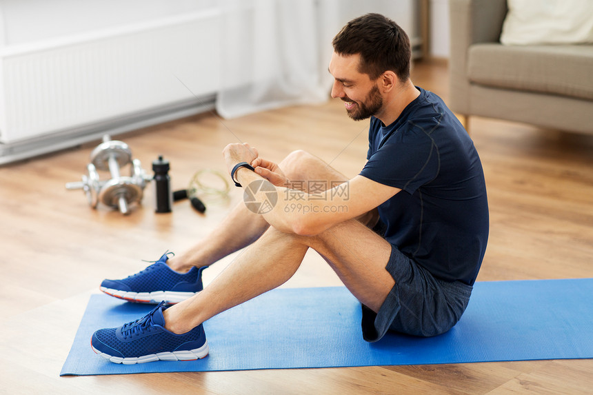 运动,技术健康的生活方式微笑的男人与健身追踪器家里锻炼带着健身追踪器的微笑的男人家锻炼图片