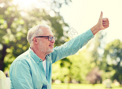 老人,手势人的快乐的老人戴着眼镜,坐夏季公园,竖大拇指快乐的老人夏季公园竖大拇指背景图片