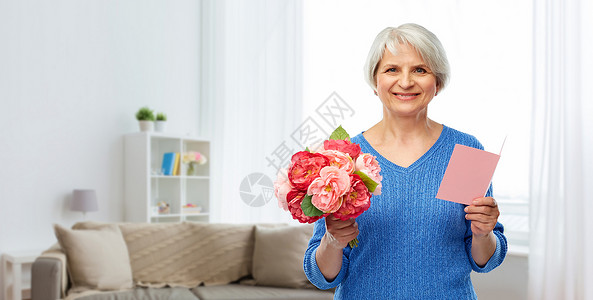 客厅里手拿鲜花和贺卡的幸福老年女人图片