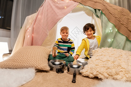 舒适度小的童潮湿的快乐的小男孩与烹饪锅播放音乐孩子帐篷家里孩子们家里的帐篷里着罐子放音乐背景