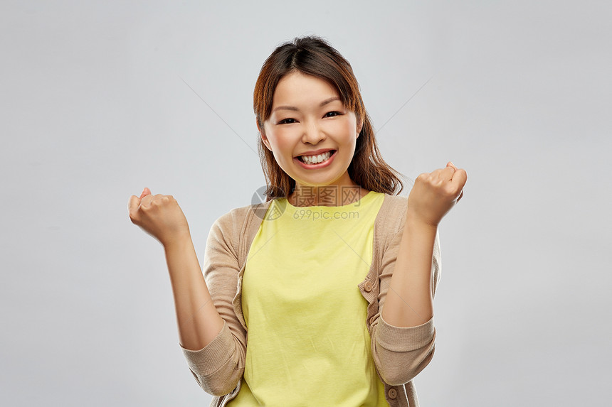 成功,胜利的姿态人们的快乐的轻亚洲妇女庆祝胜利的灰色背景快乐的亚洲女人庆祝成功图片