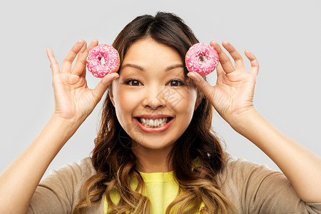 人,快餐趣的快乐的亚洲轻妇女与甜甜圈灰色背景带甜甜圈的快乐亚洲女人图片