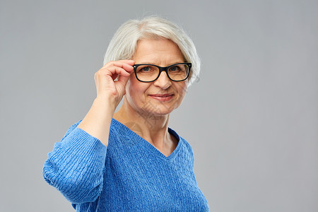 老妇女手扶眼镜框微笑图片