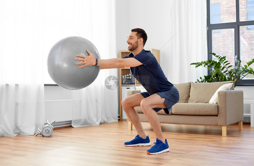 健身,运动健康的生活方式微笑的男人锻炼蹲球家里男人家锻炼球蹲图片