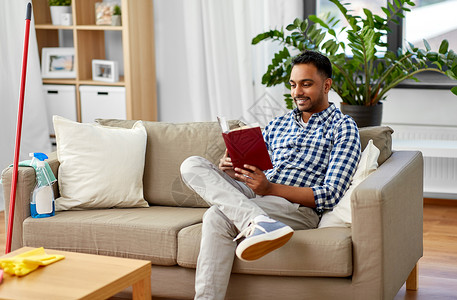 家庭人的印度男子阅读书籍休息后,家庭清洁男人看书,家打扫后休息图片