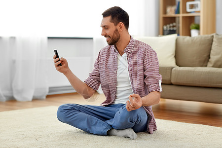 技术,瑜伽放松男人与智能手机冥想家里家里智能手机冥想的男人图片